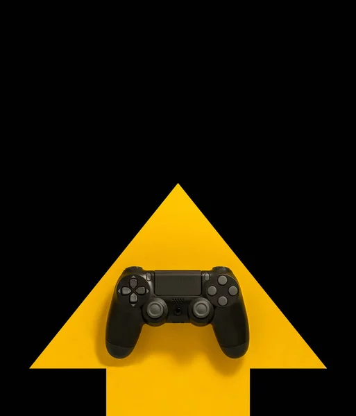 Modern black gamepad on a yellow arrow on a black background. Jo — Stock Photo, Image