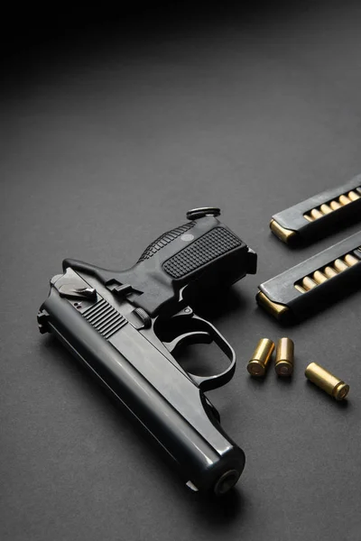 Uma pistola preta moderna e munições em fundo escuro. Armas — Fotografia de Stock