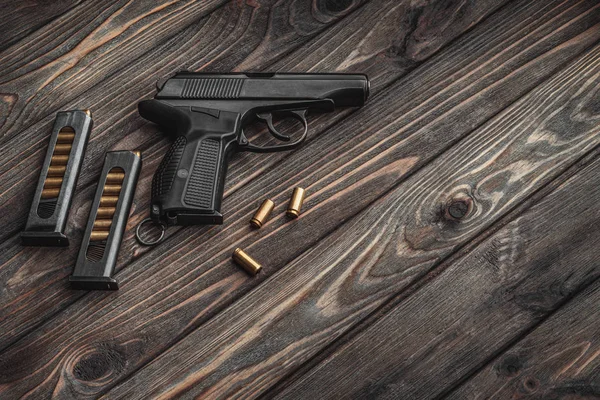 深色木制底座上的现代黑色手枪和弹药. — 图库照片
