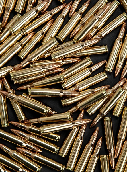Töltényhüvelyek fegyverekhez, sötét háttérrel. Fényes sárgaréz lőszer. — Stock Fotó