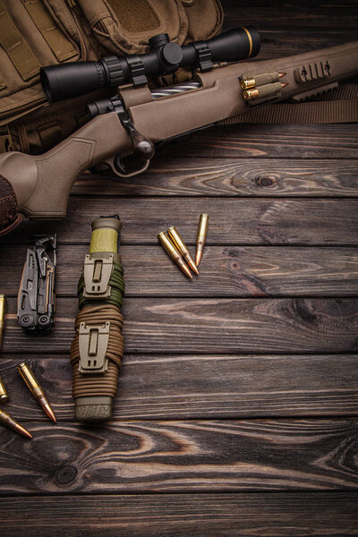 Modern bolted carbine and cartridges for it on a dark wooden tab