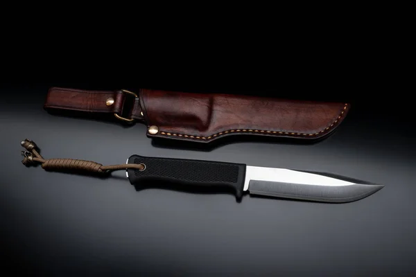 Современный охотничий нож и кожаный чехол для него на темной спине — стоковое фото