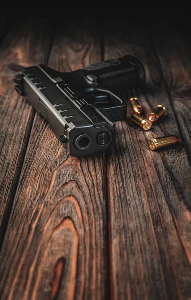 Modern black gun and ammunition  on a wooden background. Pistol. — Stock Photo, Image