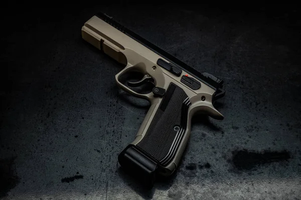 Modern brown gun on a dark background. Pistol. Weapons for sport