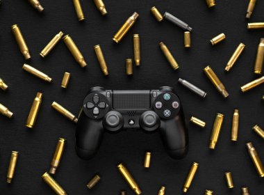 Odessa, Ukrayna 21 Eylül 2019 Gamepad Playstation 4, boş kartuşların arasında siyah ahşap bir arka planda. Silahlı çatışmalarla tetikçiyi ya da aksiyon oyununu gösteren bir kavram..