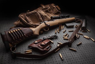 Modern sürgülü karabina ve mermiler koyu renkli ahşap bir masada. Karanlık bir arka planda teleskopik görüşlü bir tüfek. Avlanma, spor ve nefsi müdafaa için silahlar. Kartpostal konsepti.