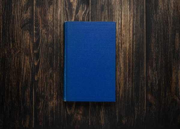 Closed book on vintage wooden background.  Old book on the wooden table. Closed book with empty cover laying on wooden table.