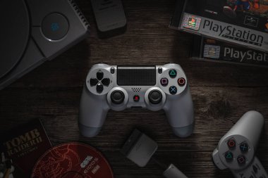 Odessa, Ukrayna - 7 Aralık 2019: The DualShock4 Wireless Controller for PlayStation 4. PS4 için PS1 konsolu arasında eski bir ahşap masa üzerinde oyun alanı grisi ve bunun için oyunlar.