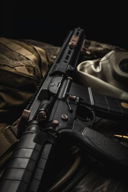 Ahşap bir masada modern otomatik karabina, sırt çantası ve gaz maskesi. Her türlü savaş koşuluna hazır bir avcı takımı..