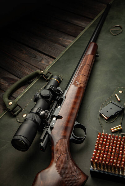 Bolt small caliber rifle 22lr with an optical sight on a wooden background. Hunting small-caliber weapon on a wooden table.