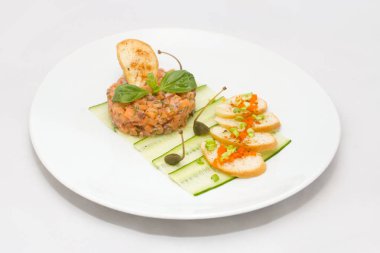 Yeşil yaprakları ile beyaz tabakta Somon tartar