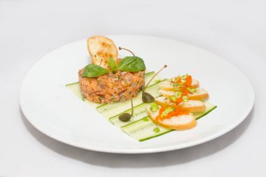 Yeşil yaprakları ile beyaz tabakta Somon tartar