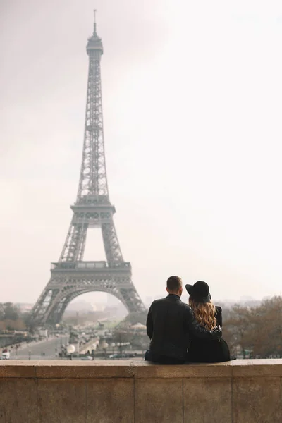 Romantic couple is seating on the backround of Eiffel tower