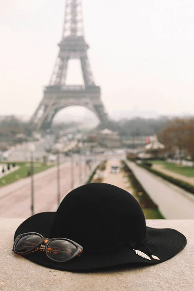 Черная шляпа лежит на фоне Эйфелевой башни — стоковое фото