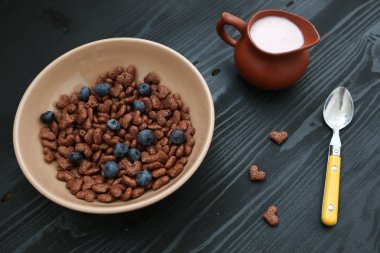 Blackberry yoğurt ahşap siyah masa üzerinde kavanoz ile bej plaka ile şeklinde Mısır gevreği kalp