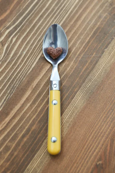 Cornflake corazón en forma de está acostado en la cuchara sobre fondo marrón de madera — Foto de Stock