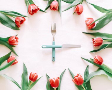 Arka plan kırmızı lale ve bıçak ve çatal üstünde o. Saat.