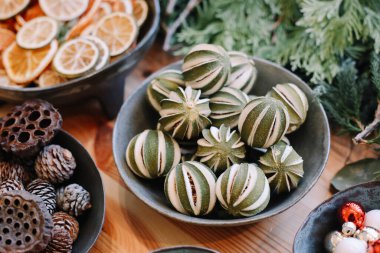 Noel çelengi için üs. Noel süsleri. Çiçekçi Noel çelengi yapıyor. Kadın eli görmek çelenk yapar. Çelenk süslemeleri. Portakallar, çiçekler kırmızı böğürtlenler, ahşap yıldızlar.