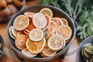 Noel çelengi için üs. Noel süsleri. Çiçekçi Noel çelengi yapıyor. Kadın eli görmek çelenk yapar. Çelenk süslemeleri. Portakallar, çiçekler kırmızı böğürtlenler, ahşap yıldızlar.