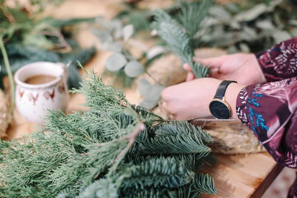 Base for Christmas wreath. Christmas decorations. Christmas wreath. Florist making Christmas wreath. View of female hands make a wreath.