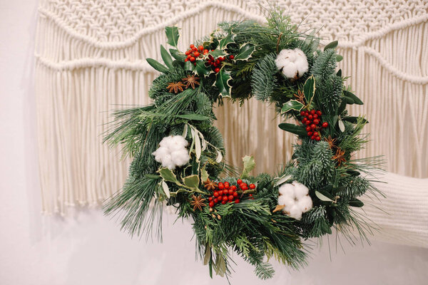 Рождественские украшения. Рождественский венок. Флорист делает рождественский венок. Вид женских рук, держащих венок
.
