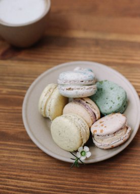 Kahverengi ahşap arka planda renkli ev yapımı makaronlar var. Bir fincan kahve.. 