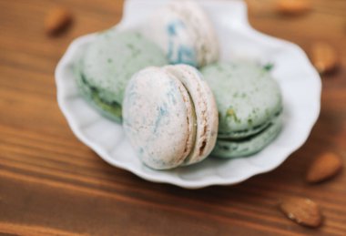 Ev yapımı yeşil ve beyaz badem kurabiyeleri ahşap kahverengi arka planda beyaz tabakta yatıyorlar.