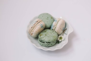 Beyaz arka plandaki beyaz tabakta ev yapımı yeşil ve beyaz makaronlar var.