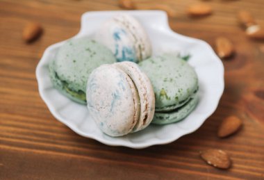 Ev yapımı yeşil ve beyaz badem kurabiyeleri ahşap kahverengi arka planda beyaz tabakta yatıyorlar.