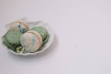 Beyaz arka plandaki beyaz tabakta ev yapımı yeşil ve beyaz makaronlar var.