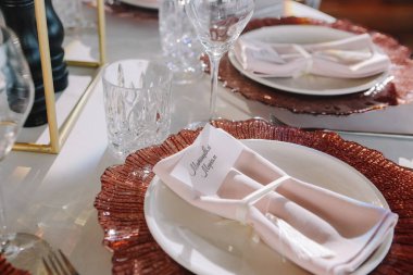 Düğün için. Ziyafet. Üzerinde pembe ve beyaz çiçekler ve kırmızı ve beyaz tabaklar olan cam masa çatal bıçak, çiçek ve çanak çömlek ile servis edilir..