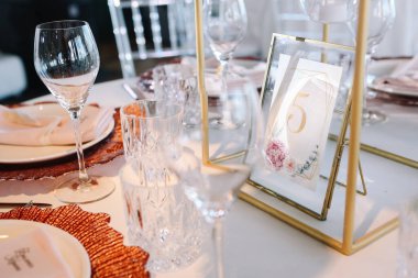 Düğün için. Ziyafet. Üzerinde pembe ve beyaz çiçekler ve kırmızı ve beyaz tabaklar olan cam masa çatal bıçak, çiçek ve çanak çömlek ile servis edilir..