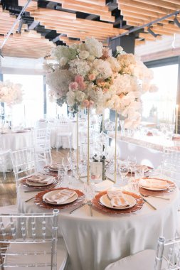 Düğün için. Ziyafet. Sandalyeler ve yuvarlak masa misafirler için çatal bıçak, çiçek ve çanak çömlek ile servis edilir ve üzerinde pembe ve beyaz çiçekler ve kırmızı tabaklar ile bir masa örtüsü ile kaplıdır.