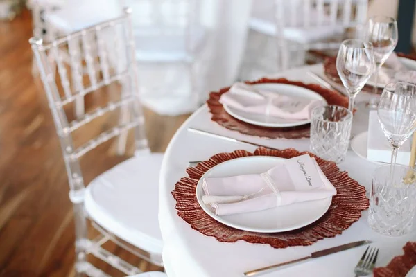 結婚式 宴会だ ピンクと白の花と赤と白のプレートとガラステーブルには カトラリー 花やクロックが添えられています — ストック写真