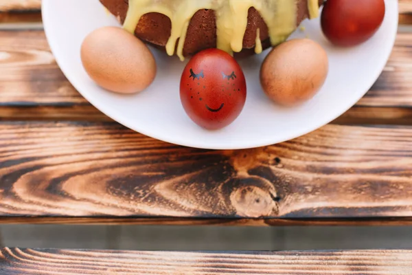 Czerwone Pisanki Uśmiechem Wokół Jaj Ciasto Wielkanocne Białym Talerzu Drewnianym — Zdjęcie stockowe