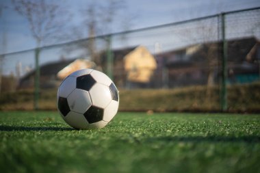 Yapay bir sahada açık bir alanda siyah beyaz bir futbol topu.