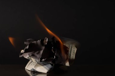 Yüz dolarlık banknot yakıyor. Karanlık bir arka planda. Yaratıcı boşluk