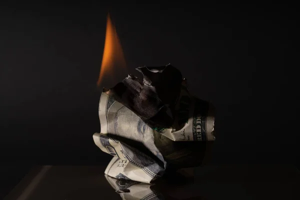 Yüz dolarlık banknot yakıyor. Karanlık bir arka planda. Yaratıcı boşluk