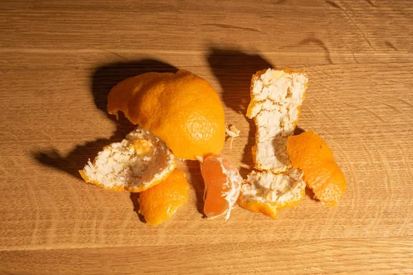Las cáscaras de mandarina en una superficie de madera sobre un fondo oscuro . — Foto de Stock