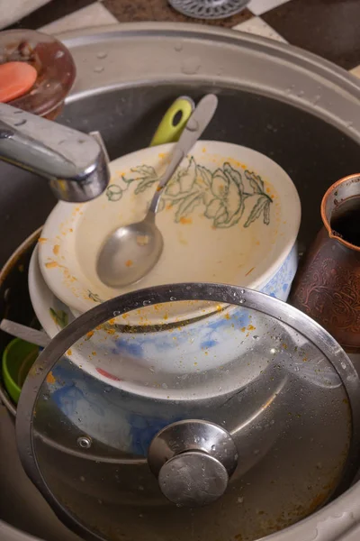 A mountain of unwashed utensils in a kitchen sink. Desolation an