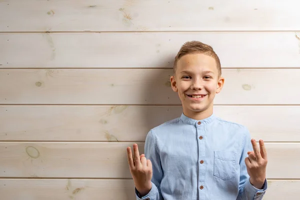 En pojke på 10 år i en blå skjorta ler på ett ljust trä b — Stockfoto