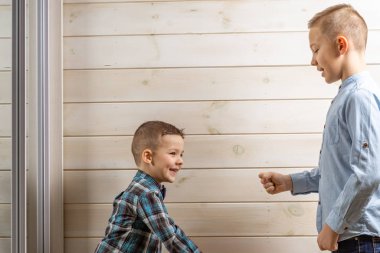 Mavi klepsi tişörtlü 4 yaşındaki bir çocuk hafif bir tahta üzerinde ağlıyor.