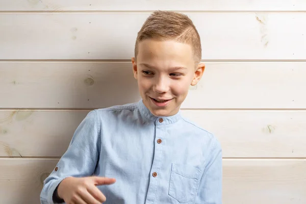 En pojke på 10 år i en blå skjorta ler på ett ljust trä b — Stockfoto