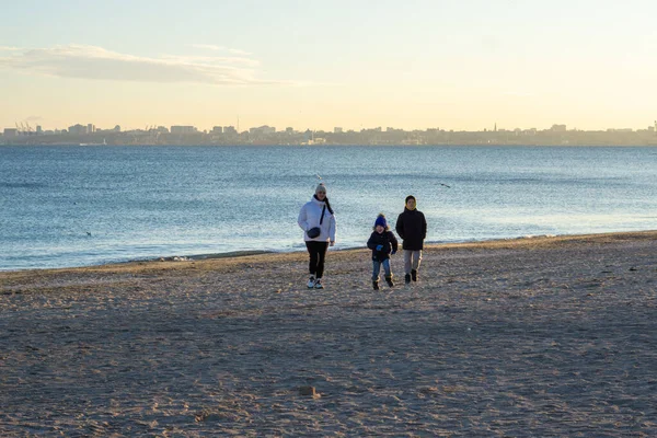 Μια γυναίκα με τους γιους της με κανονικά ρούχα ενώ περπατούσε στην παραλία μια ηλιόλουστη μέρα του χειμώνα. — Φωτογραφία Αρχείου