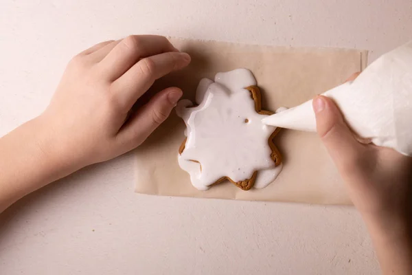 Ein 10-jähriger Junge glasiert Kekse mit einem Kochbeutel. handgefertigt. — Stockfoto