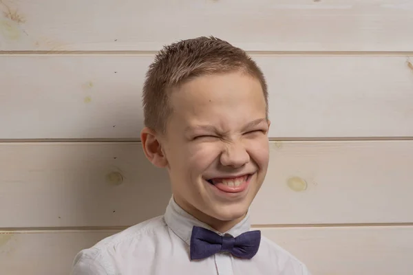 Ένα αγόρι 10 ετών χαμογελάει στο φόντο ενός ξύλινου γοφού. — Φωτογραφία Αρχείου