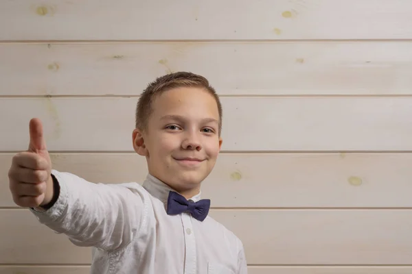 Un garçon de 10 ans sourit et montre le symbole ok sur un bois — Photo