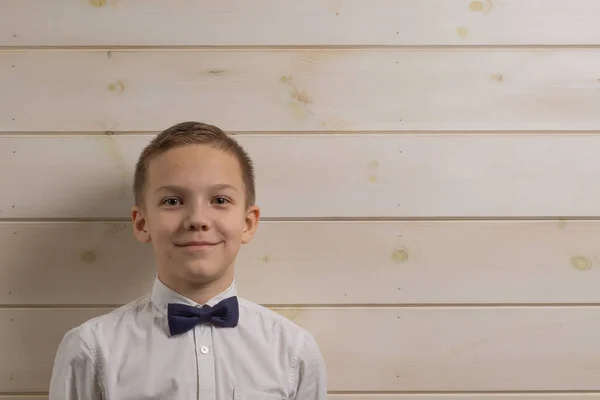 A boy of 10 years old is smiling on the background of a wooden w — Stock Photo, Image