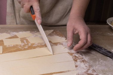 Bir kadın hamuru beyaz seramik bir bıçakla kare kare keser.. 