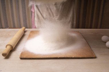 Bir kadın süzgeçten un geçirir. Çizgi film kesme tahtası, tahta